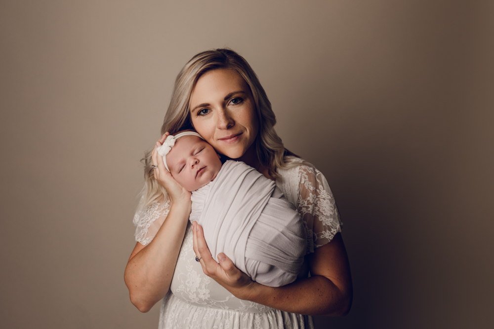 Beautiful photo of mom and her baby dressed in white with a cream backdrop