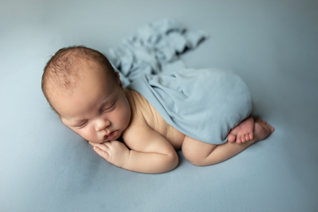 baby boy wrapped in a blue blanket during a newborn photography session