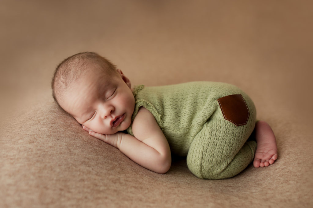 Newborn baby boy dressed in green during a newborn photography session