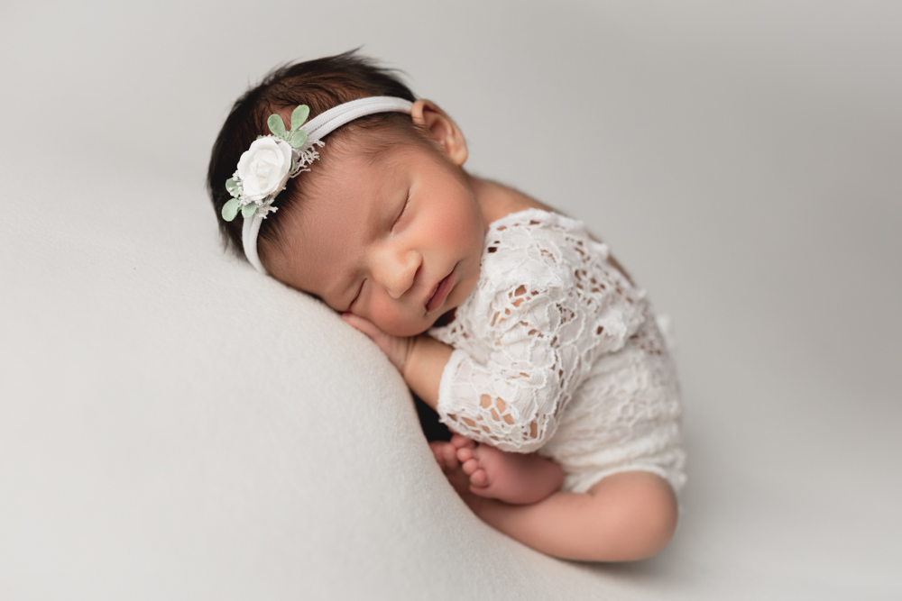 Baby girl wearing white during a newborn photography session
