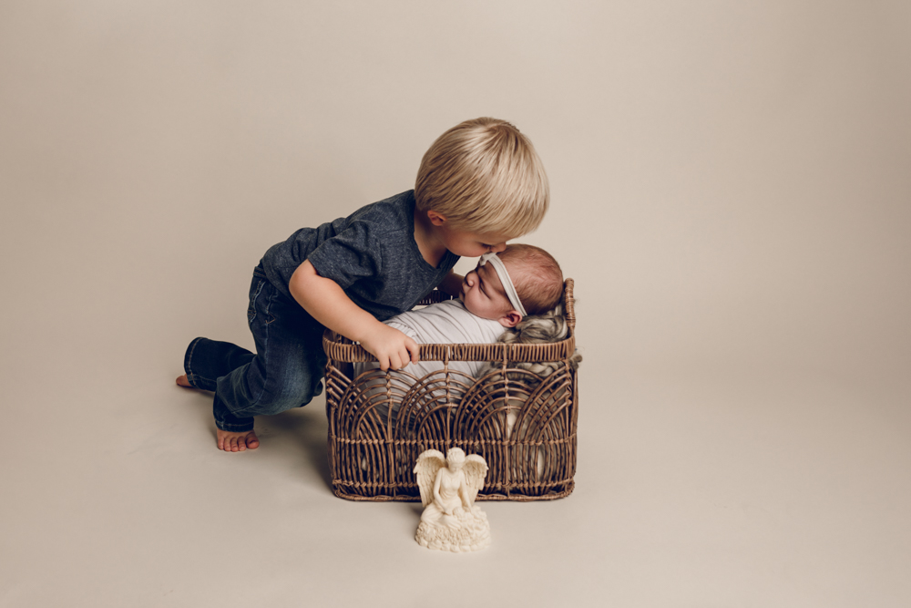 Newborn baby girl in white in a basket  during a newborn photography session