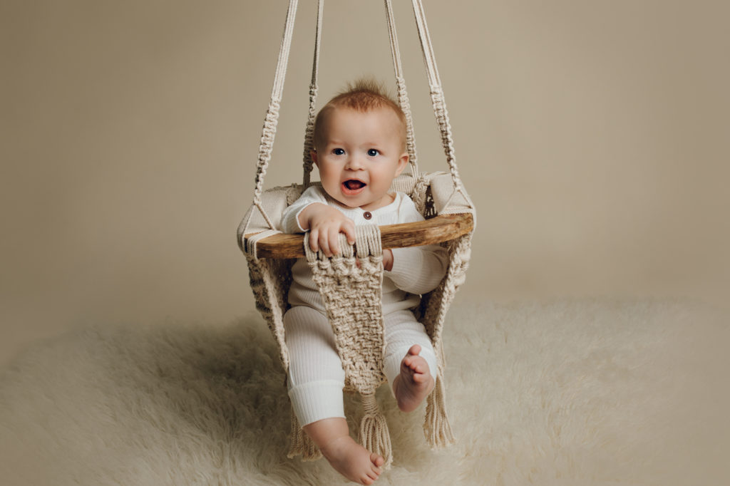 Image of a baby boy in a macrame swing during a photo session.