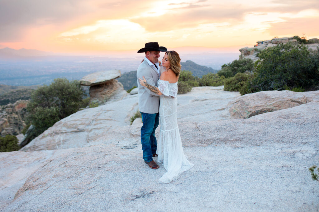 Couple enjoying their first dance after their elopement ceremony. They are on top of a desert mountain with a beautiful Arizona sunset behind them.