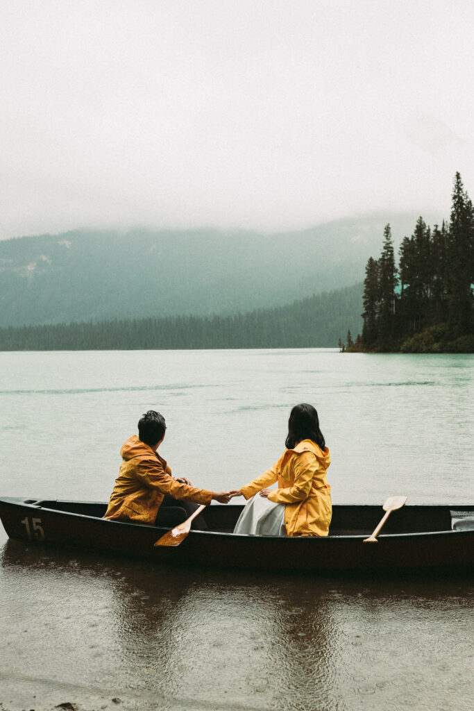 Couple sit together in a canoe in Banff National Park. They just eloped and are enjoying a rainy moment on the lake.