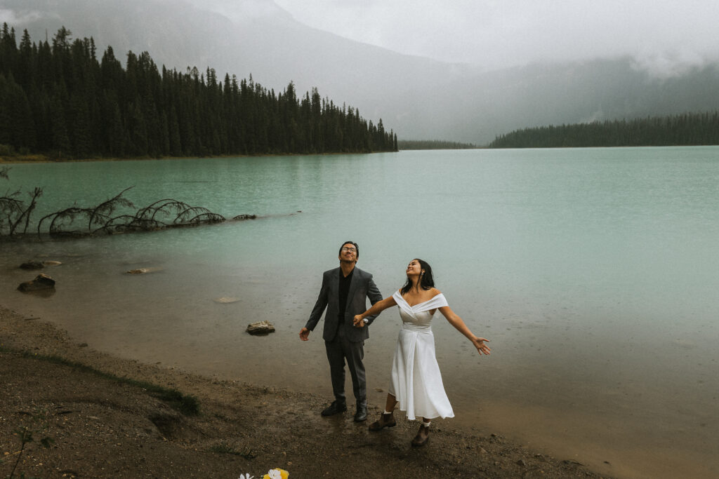 This couple looks up to the rainy sky and smiles. Even the rain can't ruin a Banff elopement.